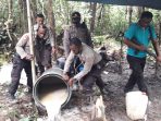 Personil Polsek Mimika Timur saat memusnahkan miras lokal jenis Sopi disaat kegiatan razia.( Foto. Humas Polda Papua)