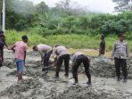 Personil polres Jayapura dibantu warga setempat saat bekerjasama membersihkan material pasir yang menutupi badan jalan jembatan kali ular.(Foto. Humas Polres Jayapura)
