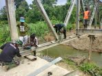 Personel Satgas Yonif 711Rks saat ikut memperbaiki jembatan rusak bersama warga di Kampung Wambes.(Foto. Pendam XVIICenderawasih)