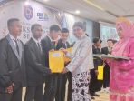 Kepsek SMKS YPKP TIK Sentani saat menyerahkan sertifikat magang BCA CMA kelas industry BCA CMA intra 4 di kegiatan purna siswa